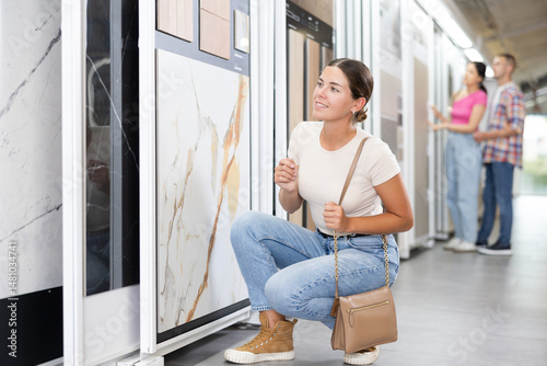 Obraz na płótnie Young woman customer selects ceramic tiles from samples in hardware store w salonie