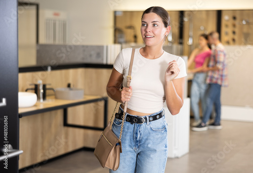 Obraz na płótnie Casual young girl looking with interest for stylish modern bathroom fixtures in specialized showroom, evaluating different options for home improvement.. w salonie
