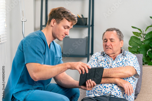Physical therapist doctor using digital tablet to explain symptoms of elderly male patient at Physiotherapy hospital clinic. Medical wellness healthcare and physical rehabilitation in elderly people.