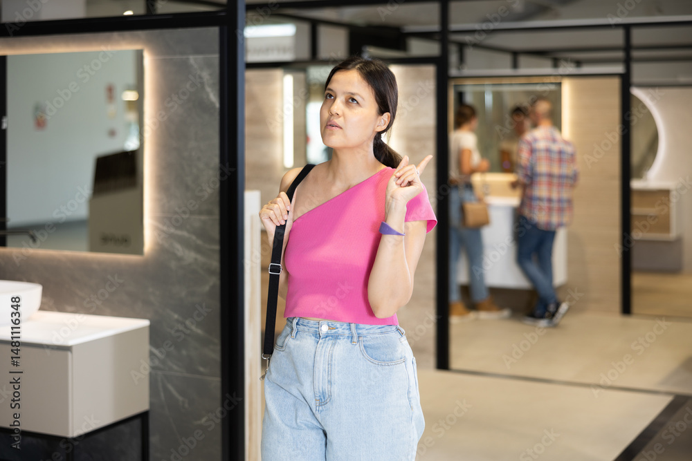 Young female shopper looking around in bathroom department of hardware store