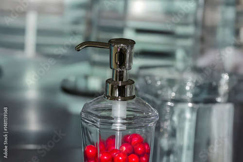 Glass container with pump filled with red fruit