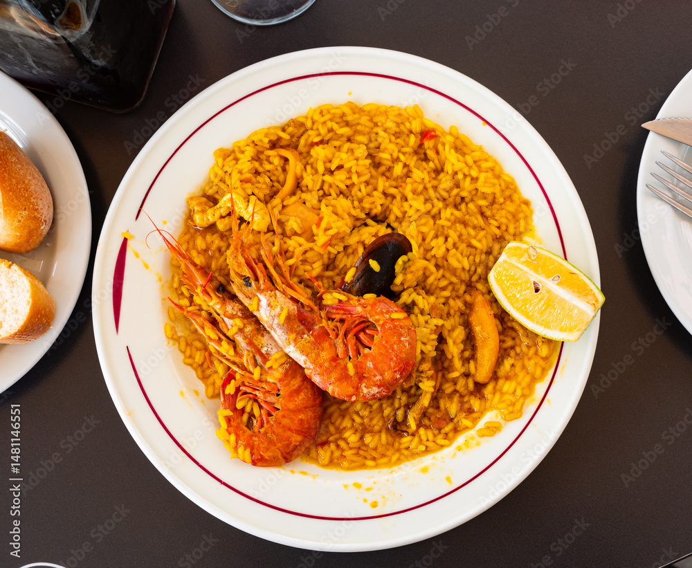 Paella made of rice and different seafood served in plate with other table appointments