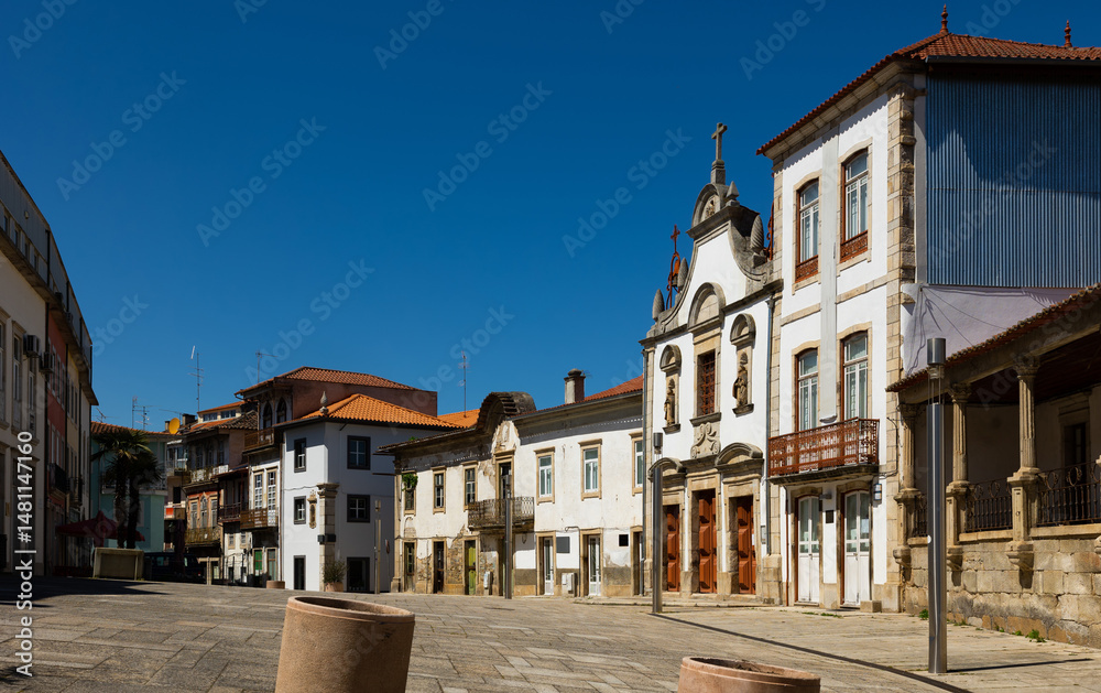 View of typical cobbled street of Portuguese city of Mirandela with old houses and medieval small Church of Mercy on sunny spring day, Braganca