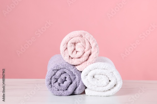 Clean towels on light marble table against pink background
