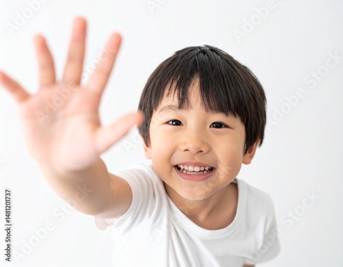 Smiling Japanese boy reaching toward a top-down camera, white background and natural light