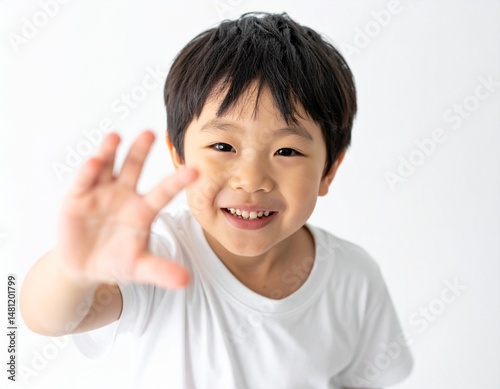 Smiling Japanese boy reaching toward a top-down camera, white background and natural light