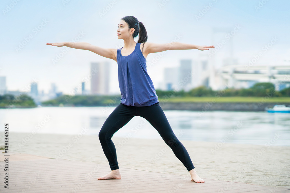 Fototapeta premium 都市のビーチでヨガをする若い女性