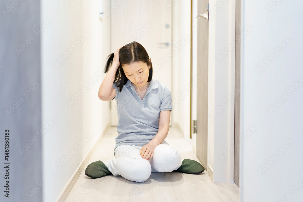 疲れて、廊下で座り込む中年女性 疲れて、廊下で座り込む中年女性