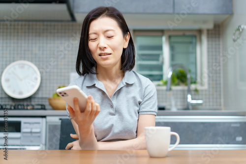 ストレスを抱えた表情でスマホを見る女性