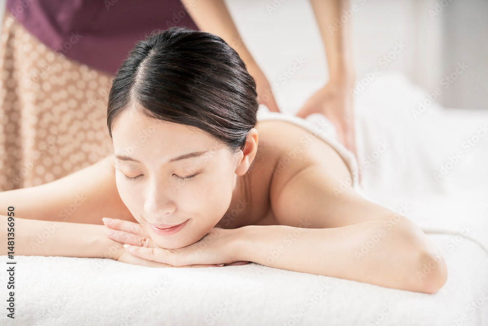 Fototapeta premium 明るい雰囲気のエステサロンでマッサージを受ける若い女性