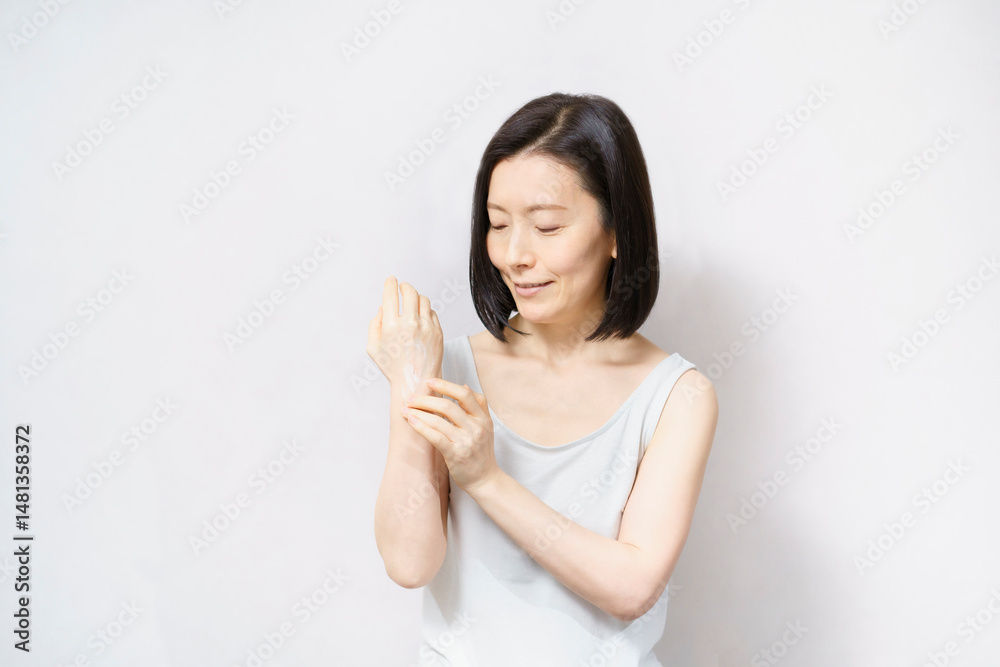 手の甲にクリームを塗る女性 手の甲にクリームを塗る女性