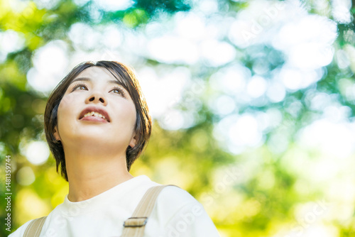 森の木々を見上げる女性