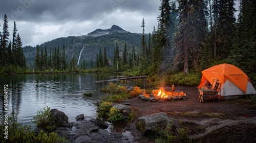 A peaceful campsite beside a lake with a glowing campfire and orange tent, surrounded by pine trees and mountains under a cloudy sky.