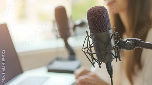 Close-up of two microphones and a person typing on a laptop.