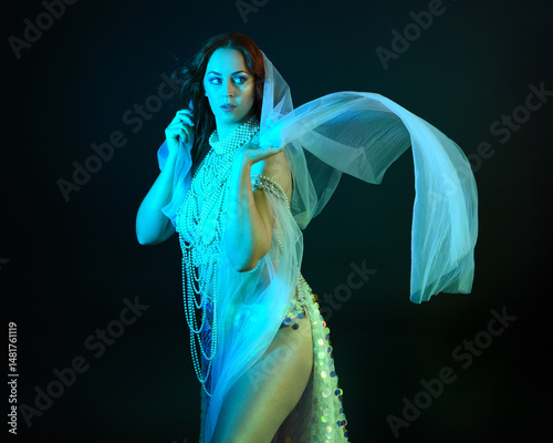 Fantasy studio portrait of a red-haired mermaid faery model wearing white pearl gown, fairytale costume. classical pose holding treasure, with flowing fabric, ethereal moody studio lighting