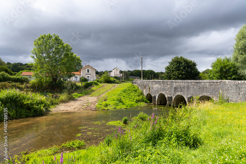 Old stone bridge crossing a shallow river near Thorey sur Ouche in Bourgogne Franche Comte, France photo