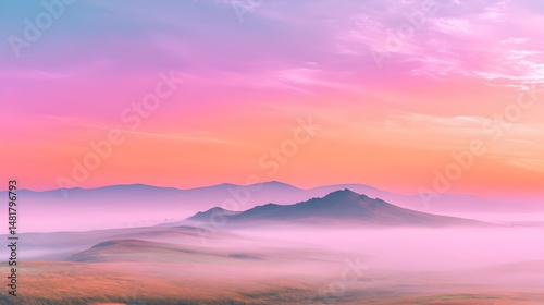 Hill silhouette under a peach pink sky with fog covering a tranquil landscape at dawn