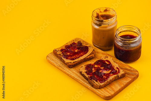 Peanut butter and jelly toast on wooden board with jars