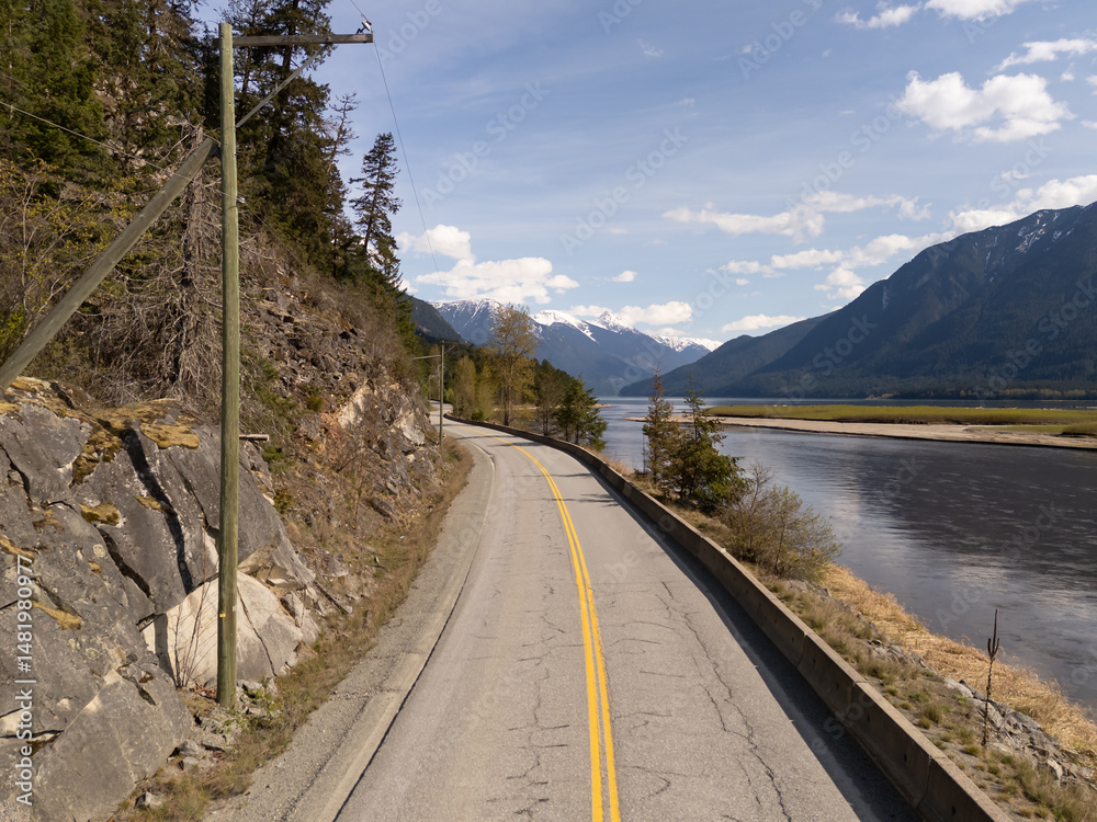 Obraz premium Scenic Road by River with Mountains in BC, Canada Under Clear Blue Sky