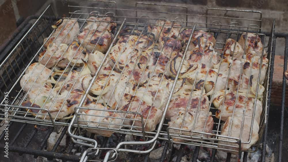 Meat kebab is on a grill grate and burning barbecue coals under it close up. Camera moving right close up along the grill grate.