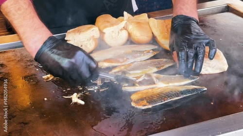 A street food vendor grills mackerel and warms bread on a swaying boat to prepare balik ekmek, a classic Turkish fish sandwich