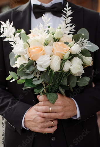 Wedding day. Groom holding a delicate wedding bouquet. Close-up