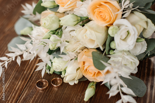 Wedding day. Photo of a wedding bouquet with gold wedding rings on a wooden background. Close-up