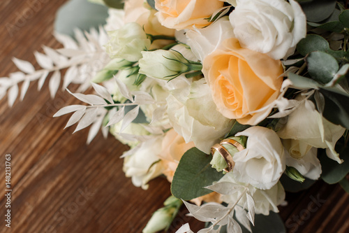 Wedding day. Photo of a wedding bouquet with gold wedding rings on a wooden background. Close-up