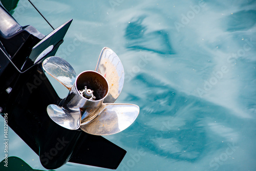 Boating and marine concept showing an outboard motor propellor against a blue water background . Good copy space