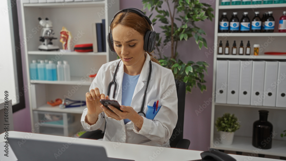 custom made wallpaper toronto digitalWoman doctor in hospital uses smartphone wearing headphones in medical office, surrounded by books and equipment, focused on device screen in professional setting.