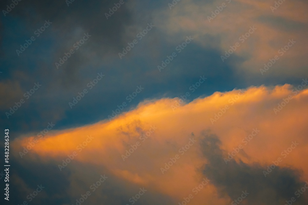 Fototapeta premium Clouds with warm, golden hues at sunset.