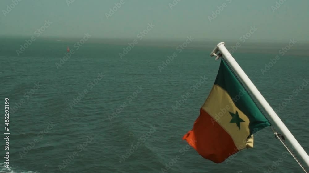 Ralenti du drapeau du Sénégal flottant au vent sur un bateau en mer – symbole national en mouvement avec l’océan en arrière-plan, tourné depuis l’embarcation en Casamance