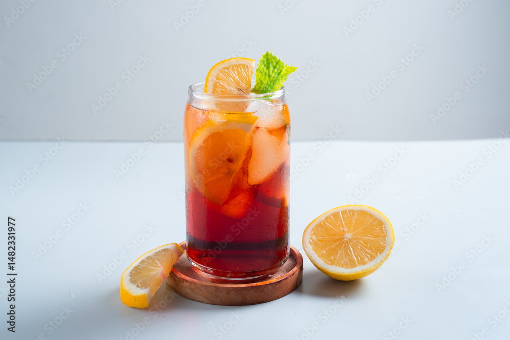 Fototapeta premium Iced tea with lemon and ice in a tall glass on a white background. The concept of a refreshing drink or lemonade on a hot summer day. Front view and copy space.