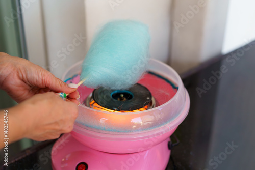 Woman making cotton candy at home using a small countertop cotton candy machine.