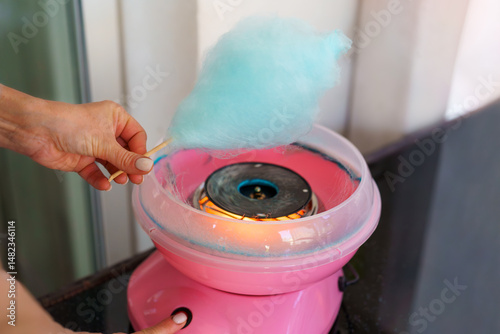 Woman making cotton candy at home using a small countertop cotton candy machine.