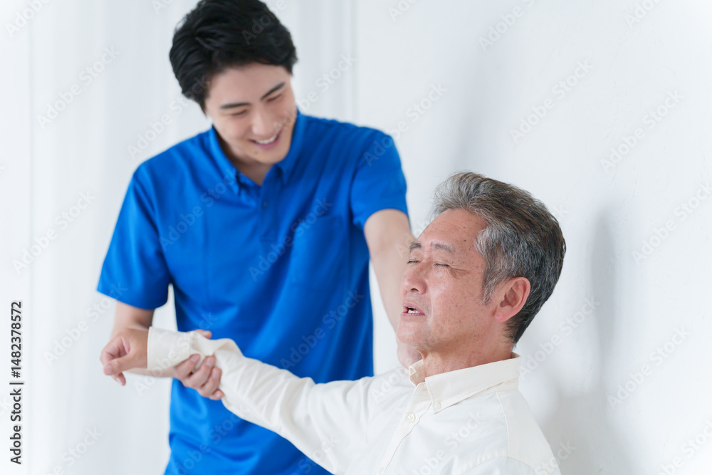 Obraz premium 肩が痛い高齢者男性とスタッフ