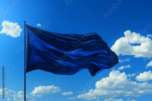 Blue flag waving in a bright blue sky with fluffy white clouds