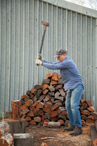 Man splitting logs of wood for fire in winter