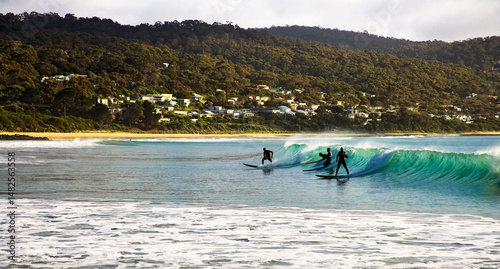 Surfers riding a break with houses and hills in background