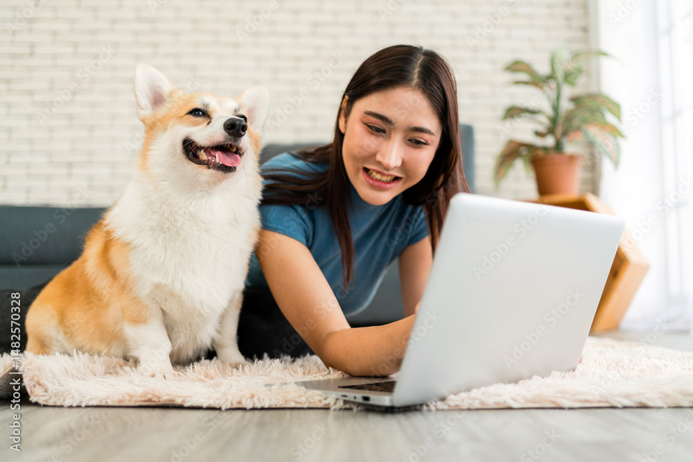 Young woman working on a laptop at home beside her smiling corgi, reflecting a cozy lifestyle, pet companionship, and remote work environment—ideal for pet care, tech use, and home life themes. Young woman working on a laptop at home beside her smiling corgi, reflecting a cozy lifestyle, pet companionship, and remote work environment—ideal for pet care, tech use, and home life themes.