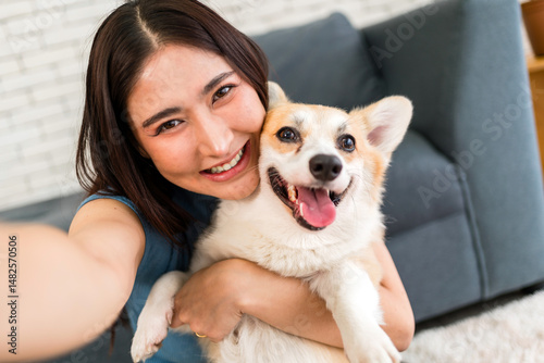 Canvastavla Smiling woman hugs her happy corgi while taking a selfie at home