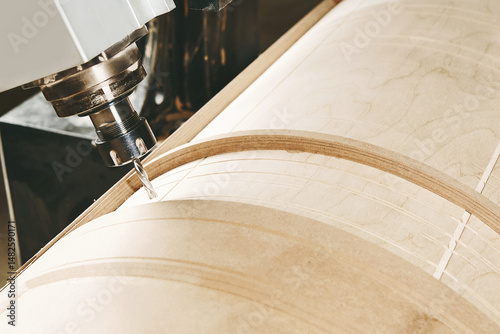 a four-axis numerically controlled woodworking machine cuts out complex lines on the canvas. CNC, computer control.