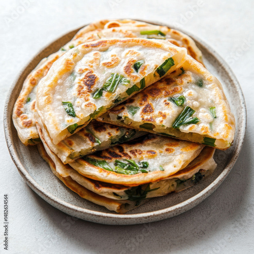 Savory Scallion Pancake Delight: A close-up studio shot presents a delectable stack of golden-brown scallion pancakes on a ceramic plate. These savory delights are layered with fresh green scallions.