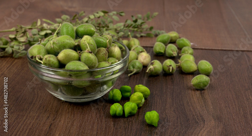 Fresh Green chickpeas on a branch, and in the pod, isolated on wooden background.
