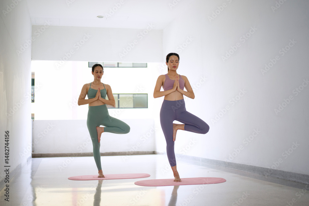 Obraz premium Two women are playing yoga at fitness center.