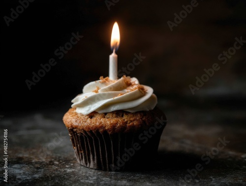 Close-up of a festive cupcake with lit candle on dark background studio shot baking concept celebration treat