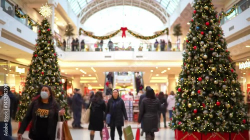 Busy shopping mall decorated with christmas trees and holiday lights during christmas season, shoppers enjoying festive atmosphere. people holiday shopping, festive decor, winter celebration
