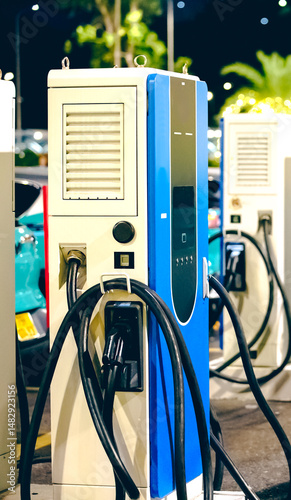 A charging station charger installed in a parking lot. Details of the housing and cable are visible, the background is slightly blurred
