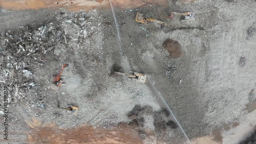 Large tracked excavator with hydraulic hammer breaks asphalt at a construction site 