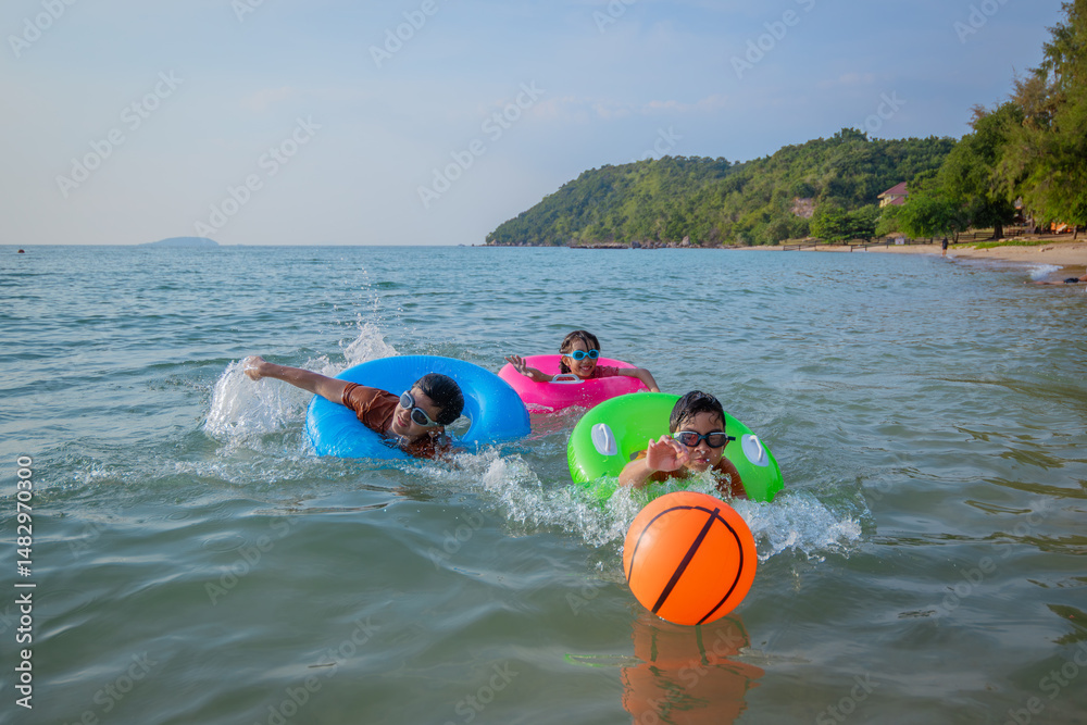 Obraz premium Children playing brightly colored inflatable rings joyful at the beach during playful and enjoying funny of summer semester vacations .